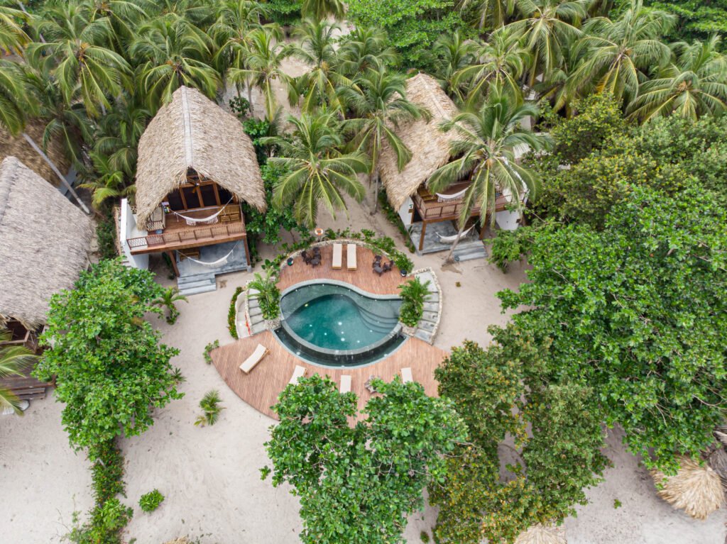 Vista aérea de la piscina infinita en forma de ojo de Casa Iwana Tayrona, entre palmeras y frente al mar Caribe