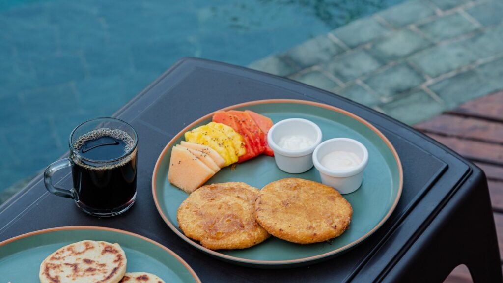 Desayuno servido en bandeja junto a la piscina infinita de Casa Iwana, con café y arepas